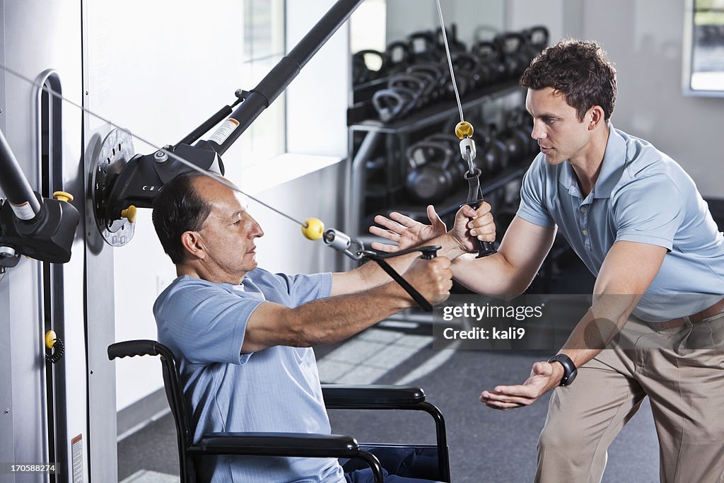 Physische Therapeuten helfen Patienten im Rollstuhl