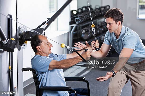 physical therapist helping patient in wheelchair - open workout stockfoto's en -beelden