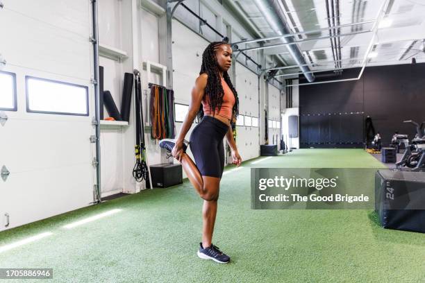 Full Length Of Young Woman Stretching Leg While Exercising At Gym High-Res Stock Photo