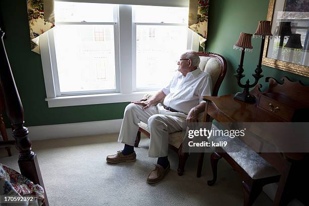 senior hombre mirando a través de una ventana - 80s living room fotografías e imágenes de stock