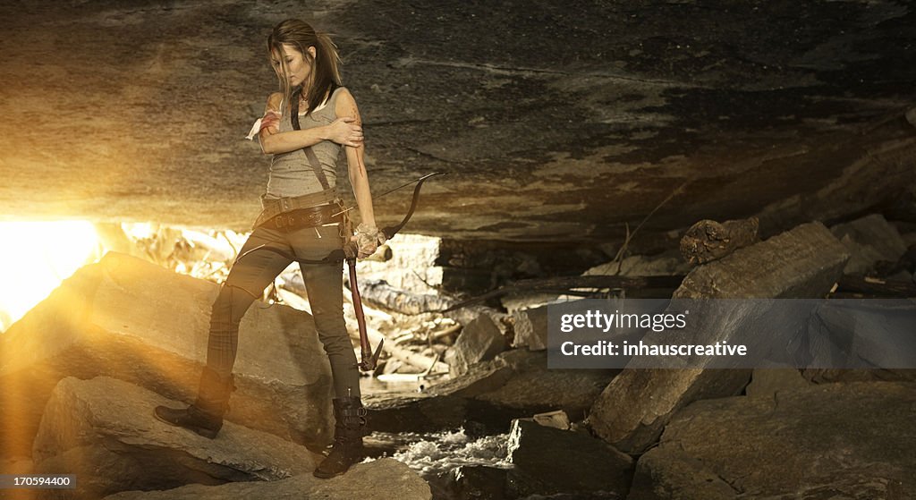 Female heroine with bow and arrow in cave