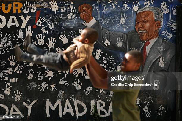 Children play next to a mural depicting former South African President Nelson Mandela near where he lived during the 1940s in Alexandra Township June...