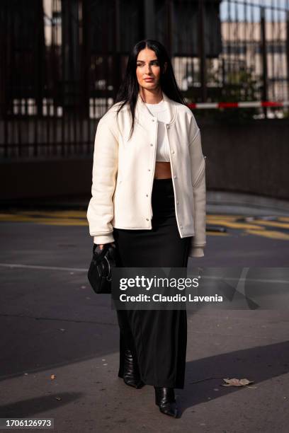 Fiona Zanetti wears a cream bomber jacket, white crop top, black long skirt and black Courreges bag, outside Courreges, during the Womenswear...