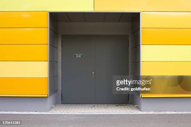 emergency exit and modern wall with yellow panels - industrial door stock pictures, royalty-free photos & images