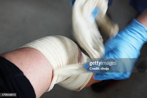 krankenschwester ist die änderung bandage zu einem verletzten patienten's knie - cut in half stock-fotos und bilder