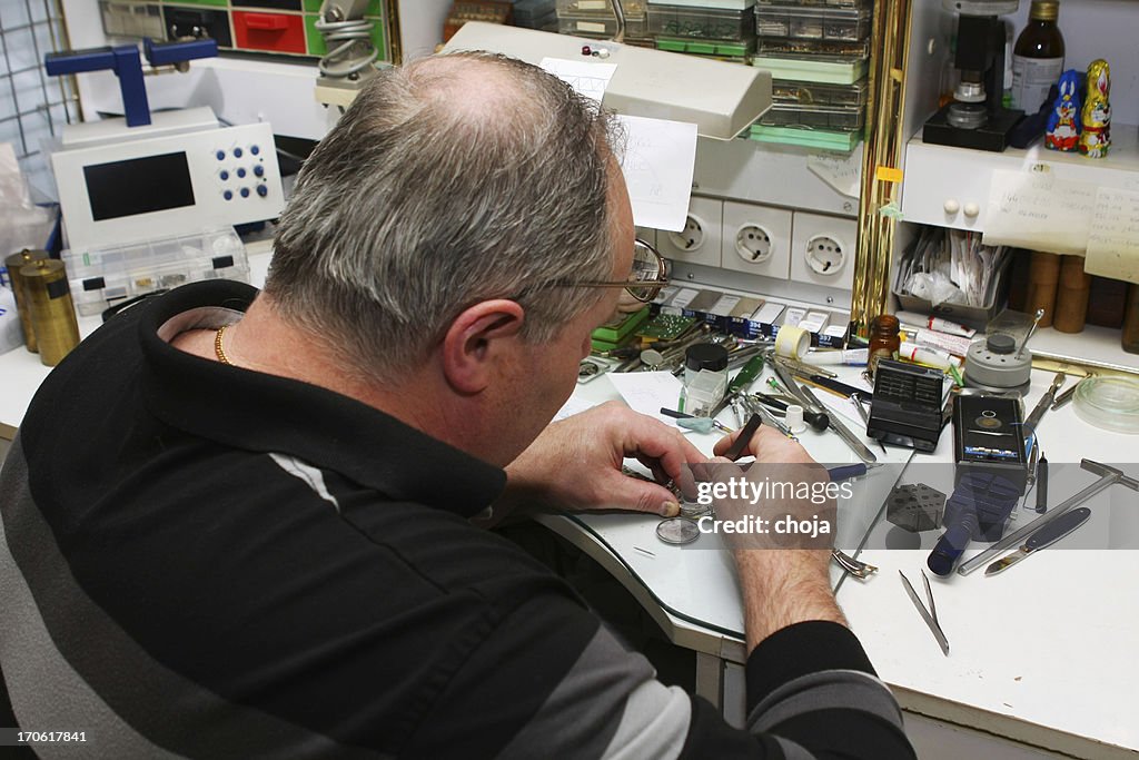 Watchmaker in his office...repairing wrist watch,chaos on the table