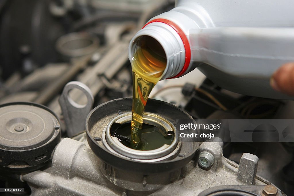 In auto repair shop...Car mechanic is changing engine oil