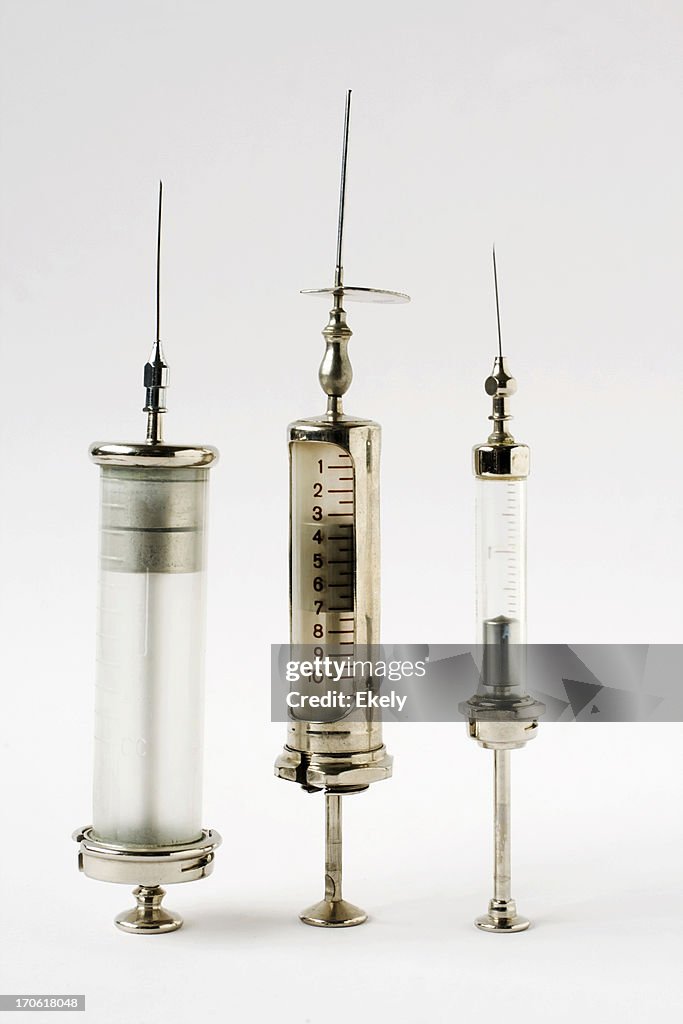 Vintage glass and steel syringes on white background.