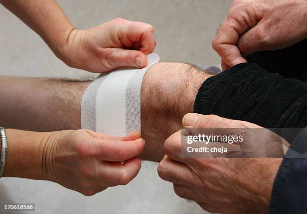 nurse at work...changing bandage to a wounded knee - applying bandaid stock pictures, royalty-free photos & images