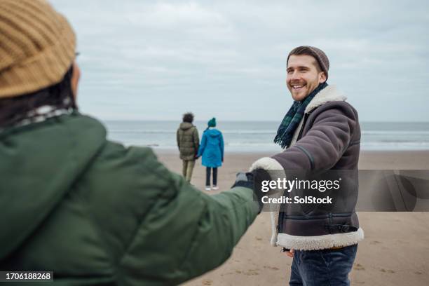 paar, das im winter den strand besucht - romantic couple walking winter beach stock-fotos und bilder