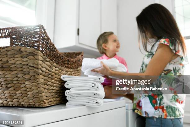 young woman and little boy doing laundry - mom laundry room stock pictures, royalty-free photos & images