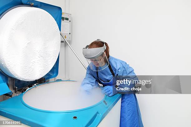 container with liquid nitrogen...doctor in hazmat suit at work - cryogenics stockfoto's en -beelden