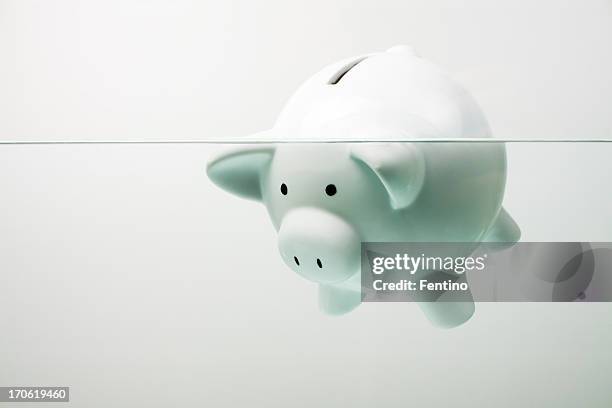 white piggy bank sinking in water - sinking stockfoto's en -beelden