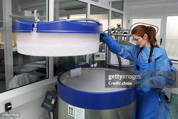 container with liquid nitrogen...doctor in hazmat suit at work - cryogenics stockfoto's en -beelden
