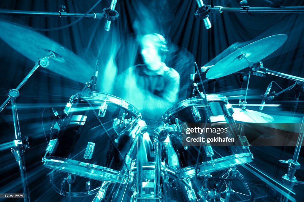 A young man playing drums in a recording studio