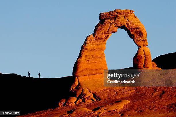 delicate arch & wanderer bei sonnenaufgang - delicate arch stock-fotos und bilder