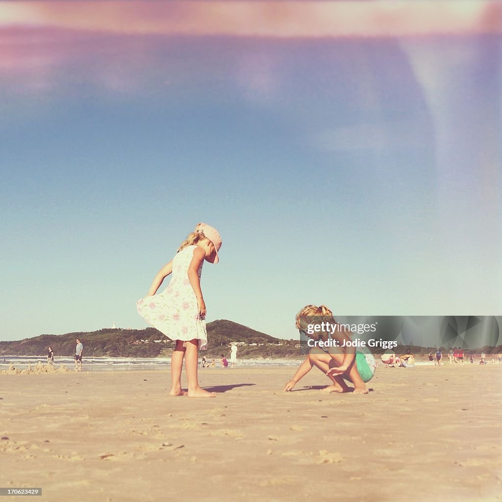 Children playing in sand on the beach on hot day