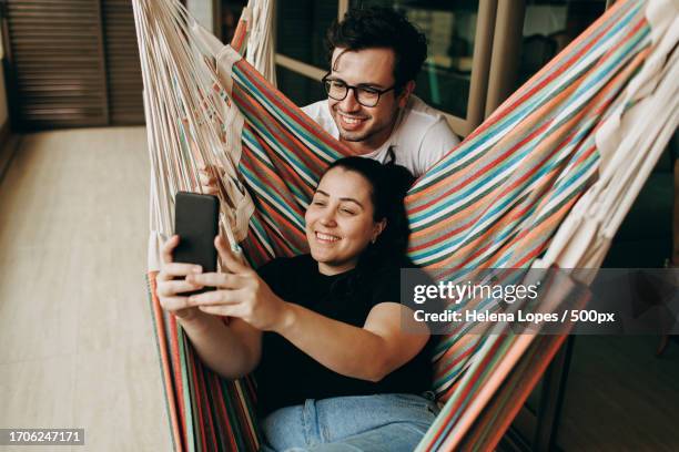 high angle view of couple listening music while lying on hammock in forest,belo horizonte,state of minas gerais,brazil - young man listening music and relaxing in hammock stock pictures, royalty-free photos & images