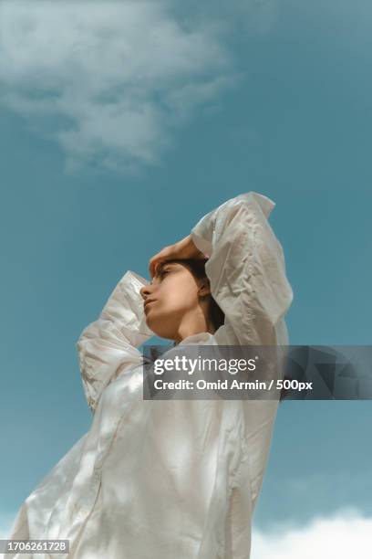low angle view of beautiful young woman in white dress shirt standing against blue sky,tehran,tehran province,iran - blue face mask stock pictures, royalty-free photos & images