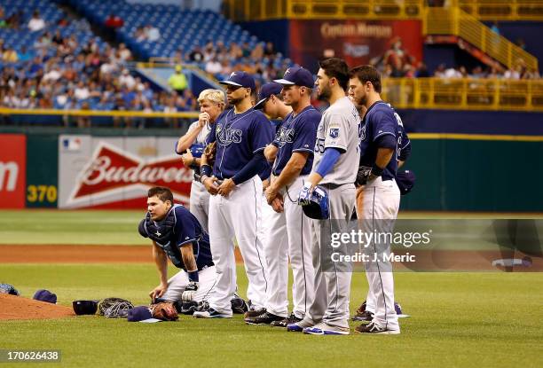 Players of the Tampa Bay Rays watch as pitcher Alex Cobb is attended to after he was hit by a line drive against the Kansas City Royals during the...