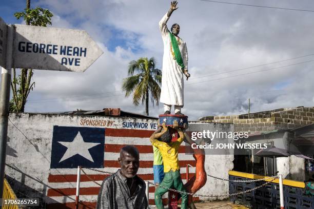 Man sits next to the a monument honoring the President of Liberia George Weah in Clara town, Monrovia on October 4, 2023. Liberia is scheduled to...
