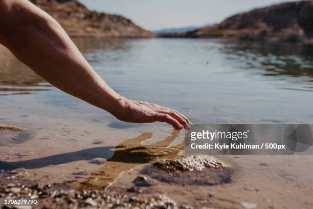 cropped hand of young man with arm in water at beach against clear sky,las vegas,nevada,united states,usa - vadear imagens e fotografias de stock