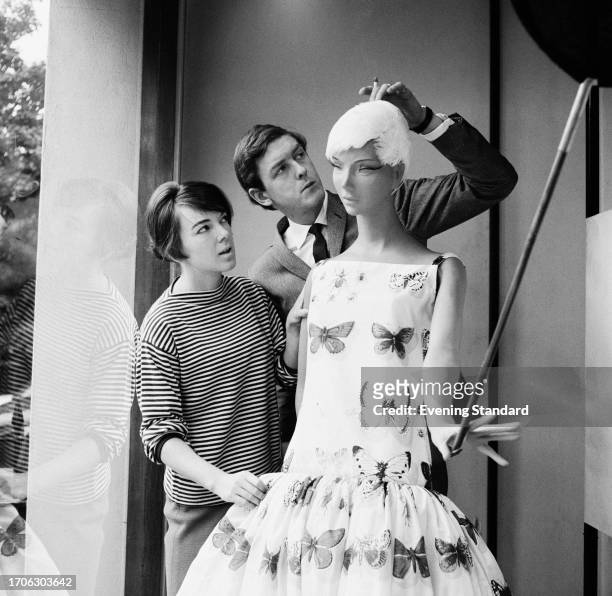 Fashion designer Mary Quant with her husband, fashion entrepreneur Alexander Plunket Greene adjusting a dressed mannequin inside the window of...