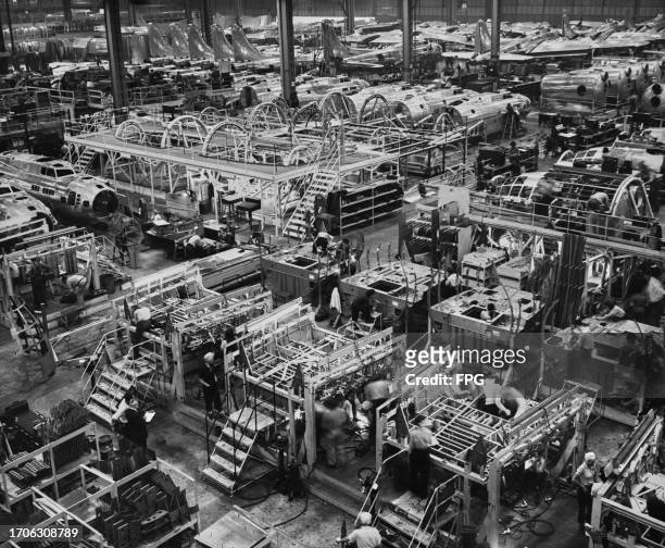 High-angle view showing Boeing employees on the shopfloor of the main assembly area with the construction of the B-29 Superfortresses in the...