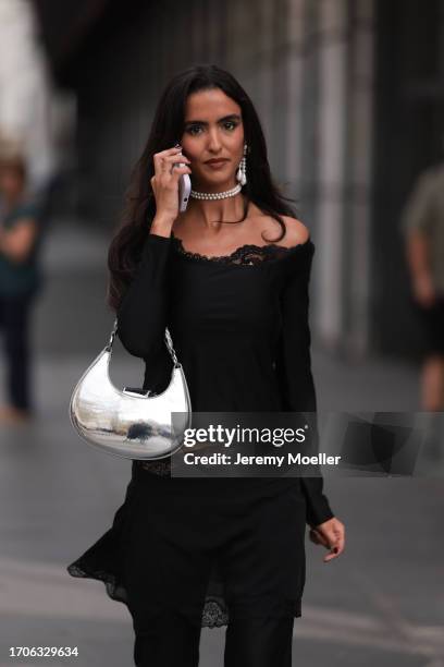 Fashion Week Guest is seen wearing pearl earrings with a pearl necklace, an off-shoulder black top with lace and a skirt with lace details, a silver...