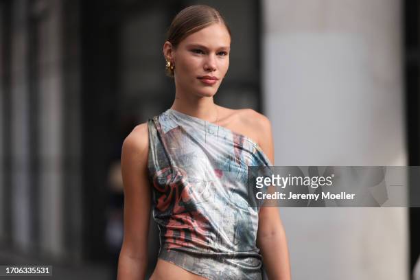 Fashion Week Guest is seen wearing gold hoop earrings, a printed one-shoulder top, low-waisted jeans and the brown leather Louis Vuitton Speedy bag...