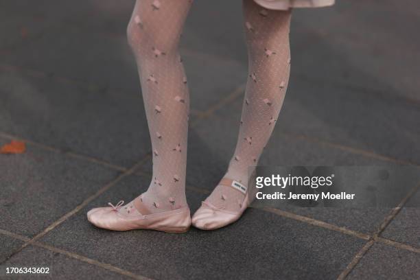 Fashion Week Guest is seen wearing pink ballerinas from Miu Miu made of satin, white tights decorated with roses during the Vaillant Show Womenswear...