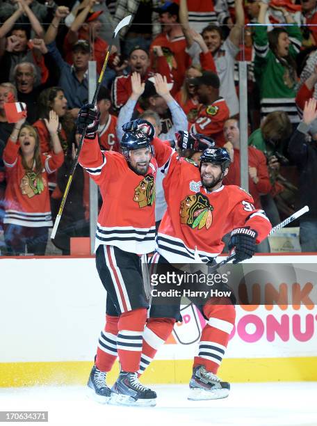 Patrick Sharp of the Chicago Blackhawks celebrates with teammate Michal Rozsival after scoring a goal in the first period against Tuukka Rask of the...