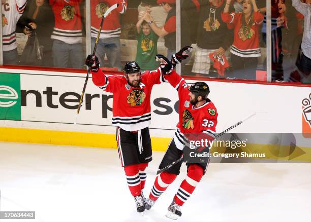 Patrick Sharp of the Chicago Blackhawks celebrates with teammate Michal Rozsival after scoring a goal in the first period against Tuukka Rask of the...