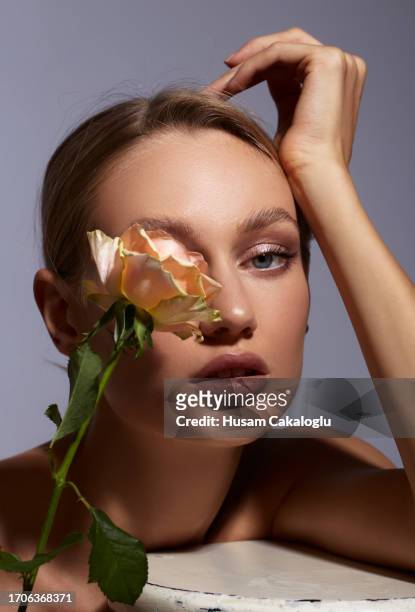 porträt einer jungen frau mit schönem gesicht, die auf weißem hintergrund liegt und eine rose vor den augen hält. - white rose flower spa stock-fotos und bilder