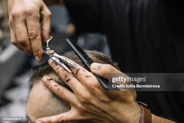 skilled hands of experienced barber sculpt masterpiece on customer head with help of scissors and black comb - haar knippen stockfoto's en -beelden
