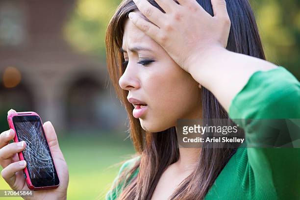 mixed race woman with shattered cell phone - broken phone stock-fotos und bilder