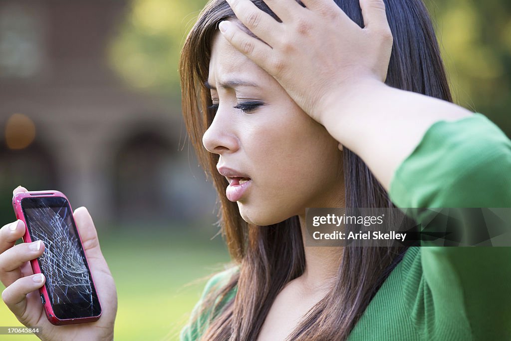 Mixed race woman with shattered cell phone