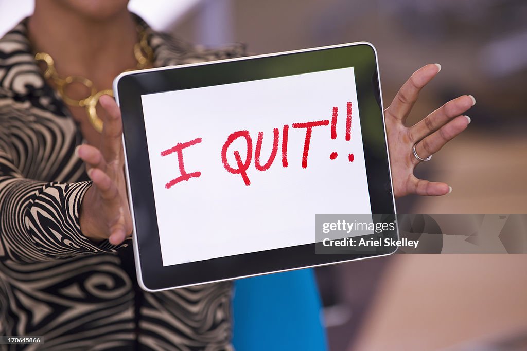 Mixed race businesswoman holding tablet computer that reads 'I quit!!