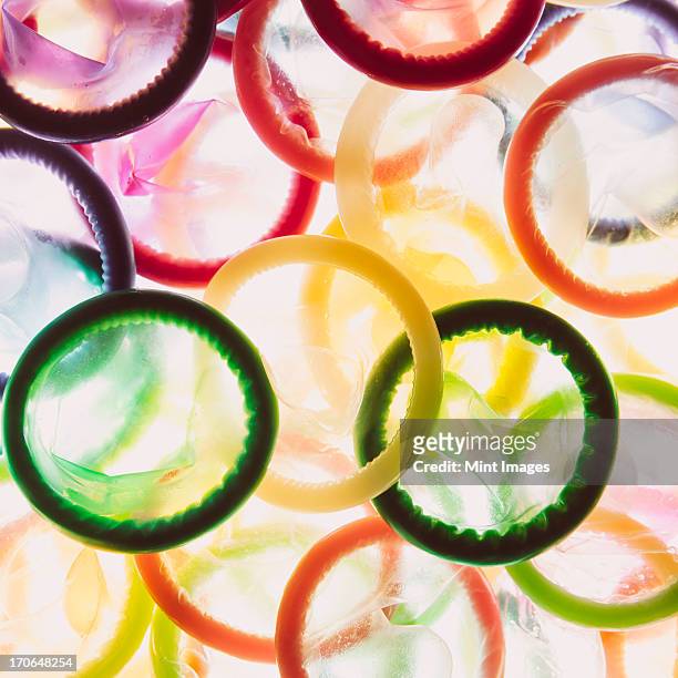 a large group of multi-colored condoms displayed on a white background. heaped up. - condoom stockfoto's en -beelden