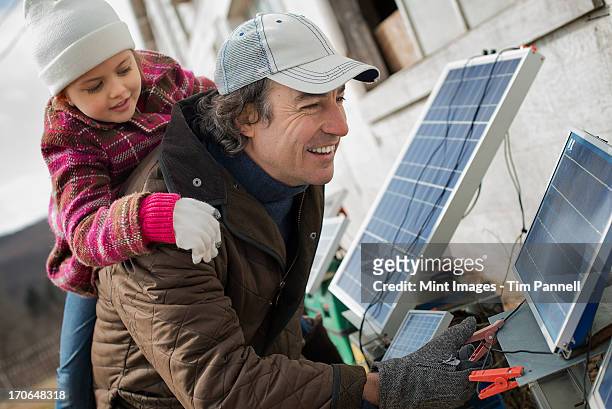 A man giving a child a piggybank while trying to connect the leads for solar power panels.