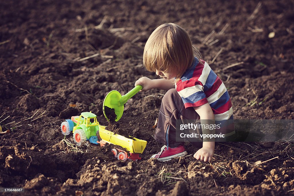 Rapaz brincando com um brinquedo de tractor
