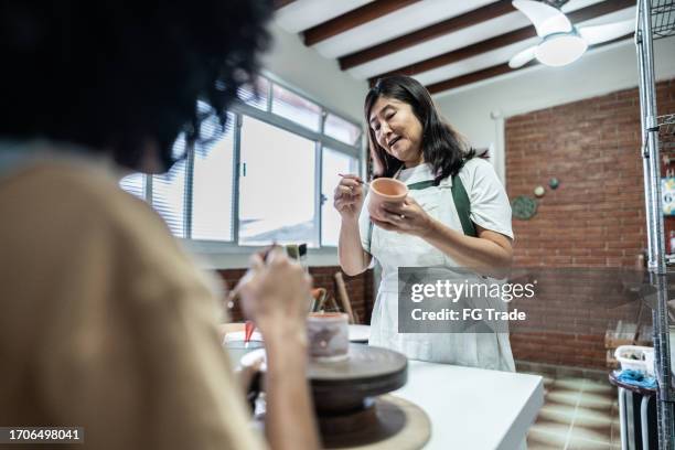 teacher teaching to paint in a ceramics workshop - east asian works of art specialist stock pictures, royalty-free photos & images