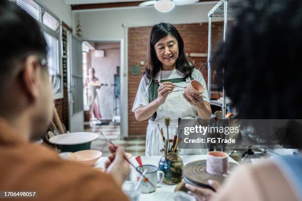teacher teaching to paint in a ceramics workshop - east asian works of art specialist stock pictures, royalty-free photos & images