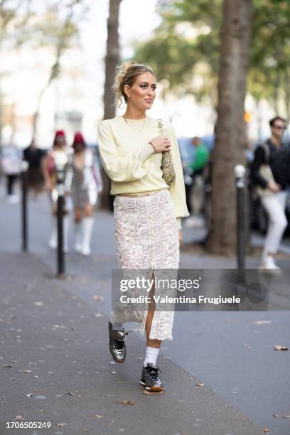 Emili Sindlev is seen wearing white socks, black sneakers, a long midi lace white skirt, a yellow long-sleeved studded sweater and a yellow and...
