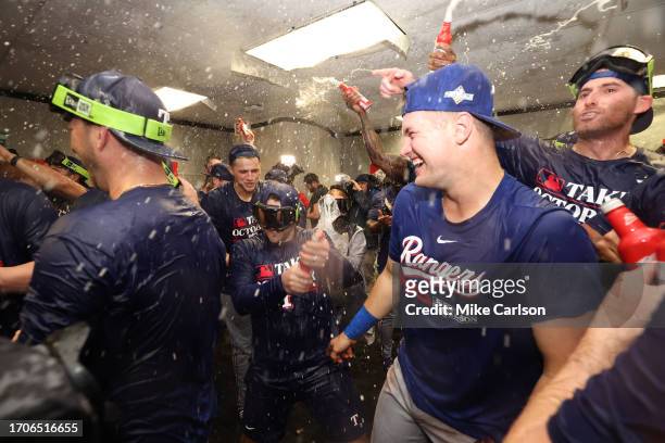 Josh Jung, Brad Miller and Corey Seager of the Texas Rangers celebrate with teammates in the clubhouse after Game 2 of the Wild Card Series between...