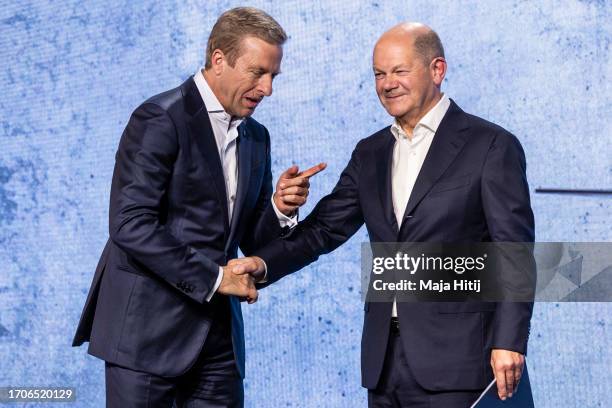 German Chancellor Olaf Scholz and Oliver Zipse, chief executive officer of BMW AG, shake hands on a stage at an event to celebrate the 100th...