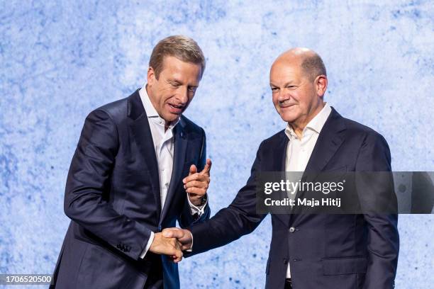 German Chancellor Olaf Scholz and Oliver Zipse, chief executive officer of BMW AG, shake hands on a stage at an event to celebrate the 100th...