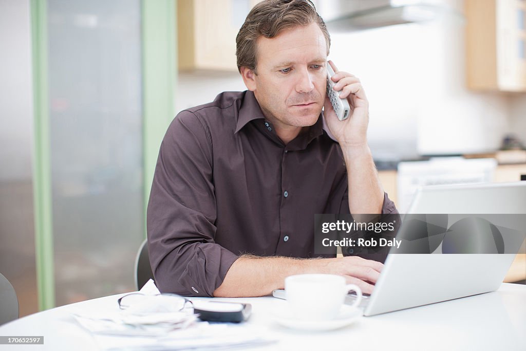 Man using laptop and talking on telephone