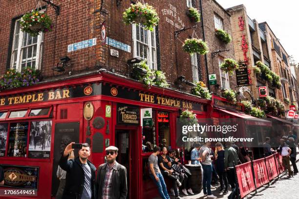 tourists taking a selfie at temple bar pub in dublin, ireland - temple bar dublin stock pictures, royalty-free photos & images