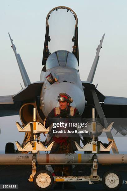 Navy sailor Danny Schotthoefer from Sisters, Oregon waits to put a side winder missile on the F-18 fighter jet behind him on the deck of the USS...